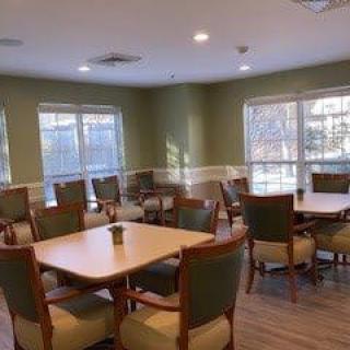 A well-lit dining room with several tables and chairs, featuring large windows that allow natural light to fill the space.