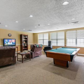 A cozy game room featuring a billiards table, television, and comfortable seating.