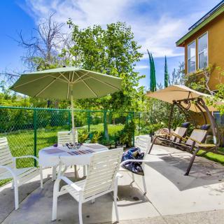 Sunny patio area with umbrella, chairs, and a garden swing.