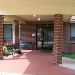 Entrance to a brick building with a covered walkway and a bench.