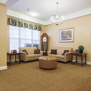 A cozy living room with sofas, a grandfather clock, and a chandelier.