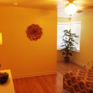 A cozy bedroom with warm lighting, featuring a ceiling fan and a potted plant by the window.