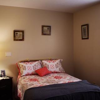 A cozy bedroom with a neatly made bed, adorned with floral bedding and framed artwork on the walls.