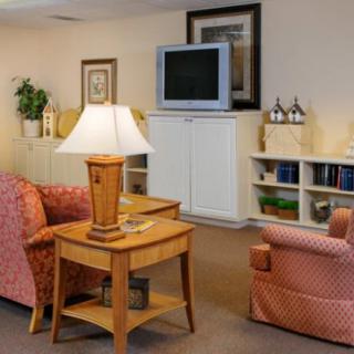 A cozy living room with a television, sofas, a lamp, and a bookshelf.