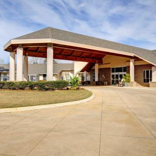 A welcoming entrance of a building with a covered driveway and landscaped surroundings.