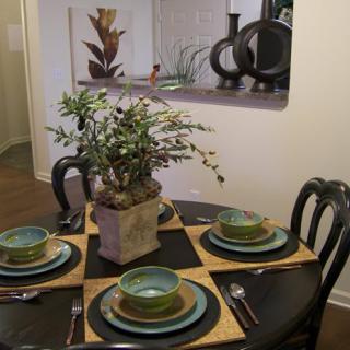A neatly set dining table with elegant dinnerware and a decorative centerpiece.