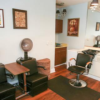 A cozy hair salon interior featuring chairs, a mirror, and wall artwork.
