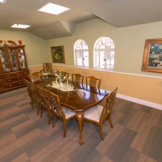 A spacious dining room featuring a large wooden table with chairs, complemented by elegant artwork and a china cabinet.