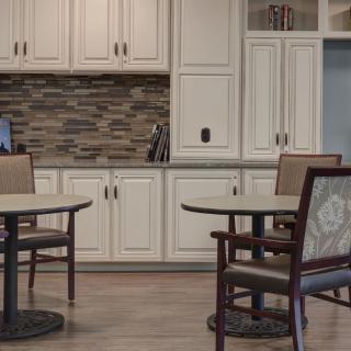 A modern kitchen interior with white cabinets and dining furniture.