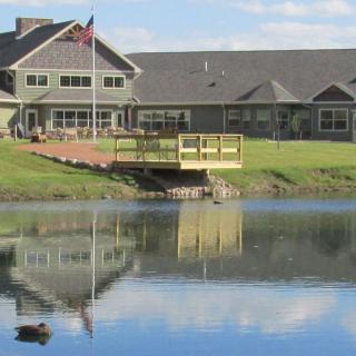 A picturesque building with a bridge over a small lake, reflecting the structure and a flag flying in the breeze.