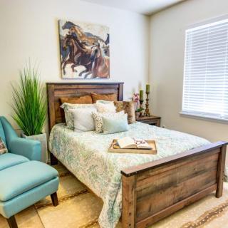 A cozy and stylish bedroom featuring a wooden bed, elegant decor, and a touch of greenery.