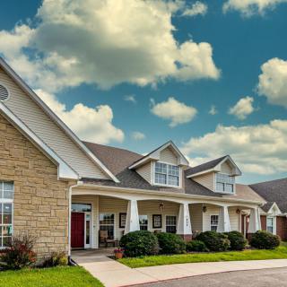 A charming suburban house with a stone facade under a partly cloudy sky.
