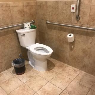 A view of a restroom featuring an accessible toilet and tiled walls.