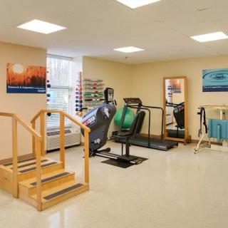 A well-equipped rehabilitation room featuring exercise machines and therapy tools.
