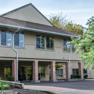 A two-story commercial office building with large windows and a landscaped exterior.