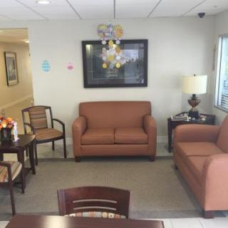 A cozy waiting area featuring comfortable sofas, a small table, and decorative artwork.