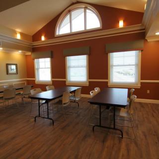 A well-lit meeting room with tables and chairs arranged on a wooden floor.