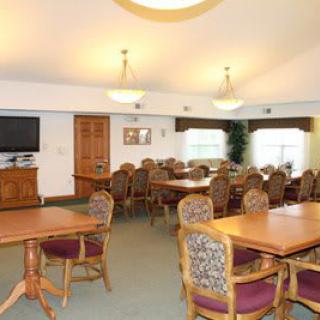 A spacious dining area with multiple tables and chairs, featuring a television and soft lighting.