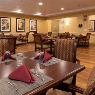 An elegantly set dining area with neatly arranged tables and comfortable chairs, featuring warm lighting and tasteful decor.
