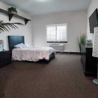 A modern and cozy bedroom featuring a neatly made bed, minimalist furniture, and natural light.