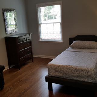 A simple bedroom with a single bed, dresser, and window lighting.