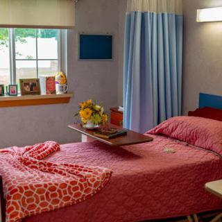 A cozy bedroom setting featuring a neatly made bed with decorative bedding, a tray for convenience, and a cheerful bouquet of flowers on display.