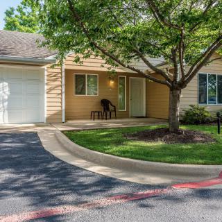 A suburban house with a garage and a tree in the front yard.