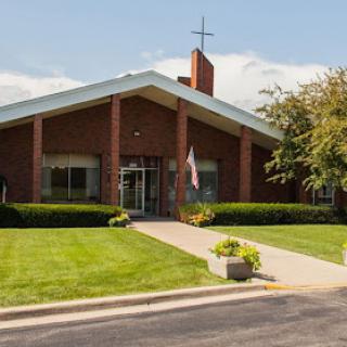 A beautiful brick church building with a cross on the roof, surrounded by well-maintained landscaping.