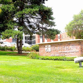 A well-maintained landscape featuring a sign in front of a brick building.