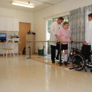 A patient undergoing physical therapy with the assistance of two healthcare professionals.