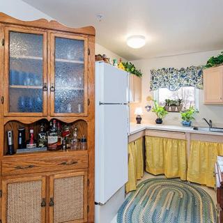 A cozy kitchen with wooden cabinets, a white refrigerator, and decorative curtains.