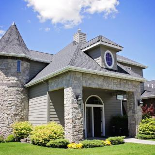 A beautiful stone house with a turret and well-maintained landscaping.