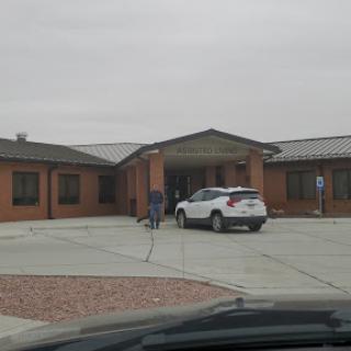 A view of a residential building on a cloudy day with a parked white car.