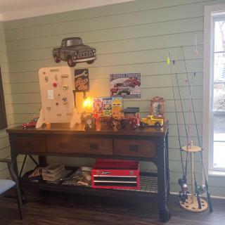 A cozy corner featuring a vintage-themed console table with toy collectibles and fishing rods.