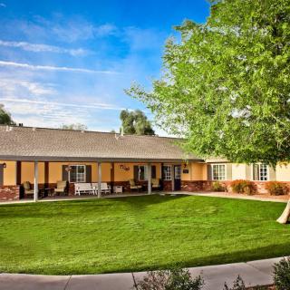 A single-story house with a well-maintained yard and lush green grass under a clear blue sky.
