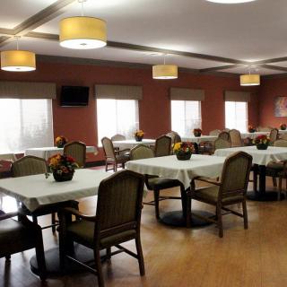 An inviting dining room featuring neatly arranged tables and chairs, with soft lighting and decor.