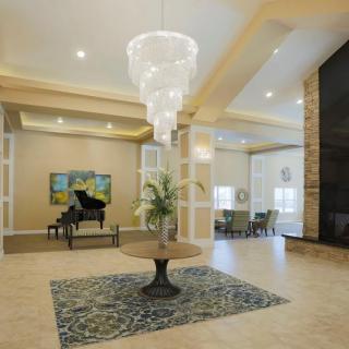 A modern lobby interior with a grand chandelier, decorative table, and a piano.