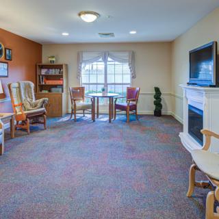 A cozy living room with chairs, a television, and a window.