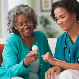 A nurse assists an elderly woman with her medication at home.