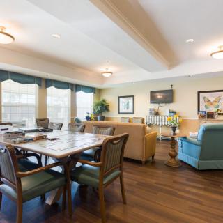 A spacious living room with a table and chairs, sofas, large windows, and a television.