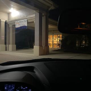 A view from inside a car looking at a brightly lit building entrance at night.