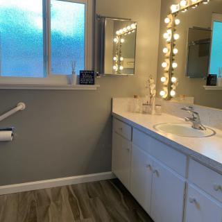 A modern bathroom with a well-lit vanity and a large mirror.