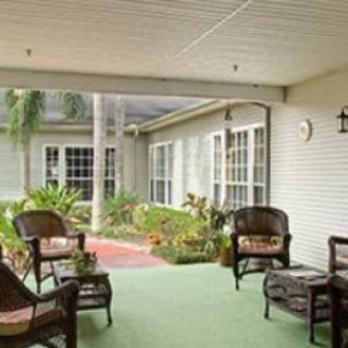 A cozy outdoor patio area with wicker chairs and a small table surrounded by greenery.
