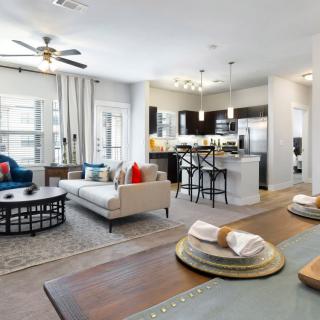 A modern open-plan living space featuring a comfortable living area, dining table, and a sleek kitchen.