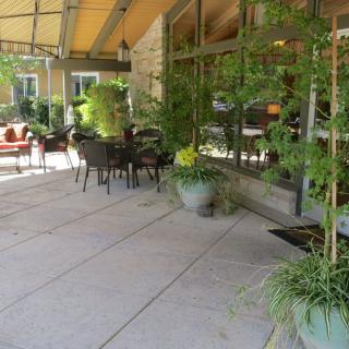 An inviting outdoor patio area with tables, chairs, and lush greenery.
