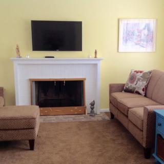 A cozy living room featuring a fireplace, wall-mounted TV, and comfortable seating.