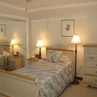 A cozy bedroom with a bed, mirrored closet, and bedside lamps.