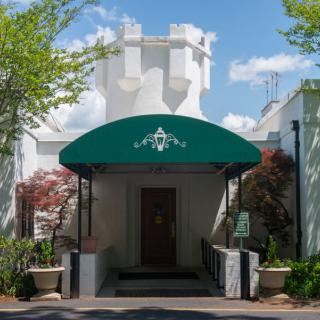 Entrance to a restaurant with a green awning and surrounding greenery.