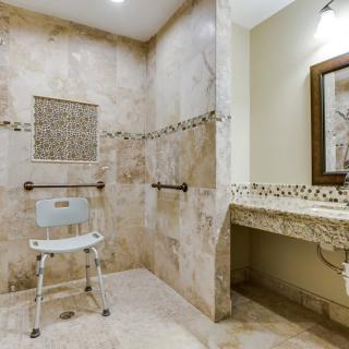 A modern, accessible bathroom with a walk-in shower and shower chair.