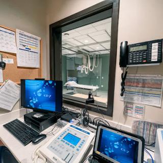 A view of a medical office space equipped with computers and monitoring devices, adjacent to a radiology room.